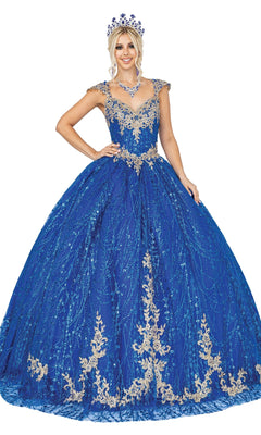 A woman models the Quinceanera Dress 1397 by Dancing Queen—a blue ball gown with gold embroidery and a sweetheart neckline—paired with a matching crown and necklace, smiling against a white background.