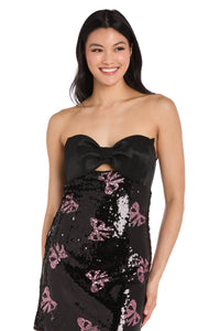 Woman wearing a black strapless dress with sequin and bow details on a white background