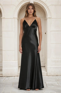 Woman wearing a black satin gown standing in front of a stone archway.