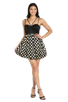 A woman smiles in the Morgan 14038 Black and Gold Bubble Party Dress, featuring a fitted top, spaghetti straps, and a flared skirt with gold polka dots. She pairs her chic semi-formal look with stylish black heels.