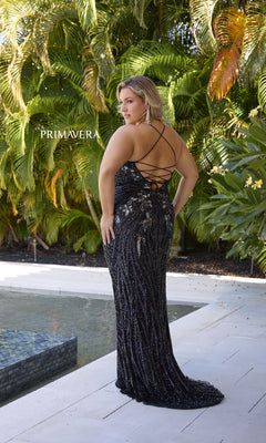 A woman in the Plus-Size Long Beaded Prom Dress: Primavera 14072, a black sequined gown with crisscross straps and open back, stands by a pool with lush green foliage. The formal dress shimmers elegantly in the light.