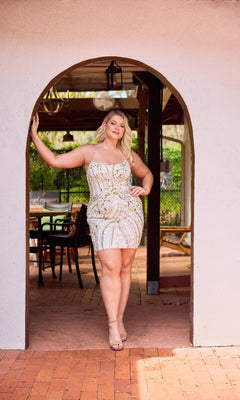 A woman wearing the Plus-Size Mini Beaded Hoco Dress: Primavera 14093 stands confidently under an arched doorway, her hand on the arch, with outdoor seating visible in the background.