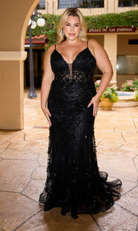 A woman in the Primavera 14106 long plus-size black prom dress stands on a stone patio under an archway, surrounded by plants and building decor.