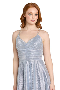 A woman with long red hair models the Morgan 14232 Short Metallic Homecoming Dress, featuring a silver sparkly fabric, decorative straps, and a chic cowl neckline, as she stands against a plain white background.