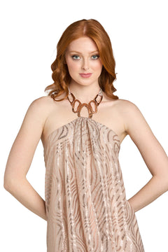 A woman with red hair is wearing the Morgan 14233A short homecoming dress, which features a beige, sequined halter neckline, and she accessorizes with a chunky necklace while standing against a plain white background.