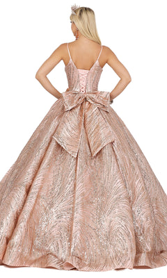 Wearing Quinceanera Dress 1447 by Dancing Queen, a woman in a pink, glittery A-line gown with a large back bow and tiara shows off delicate lace embroidery as she stands with her back to the camera.