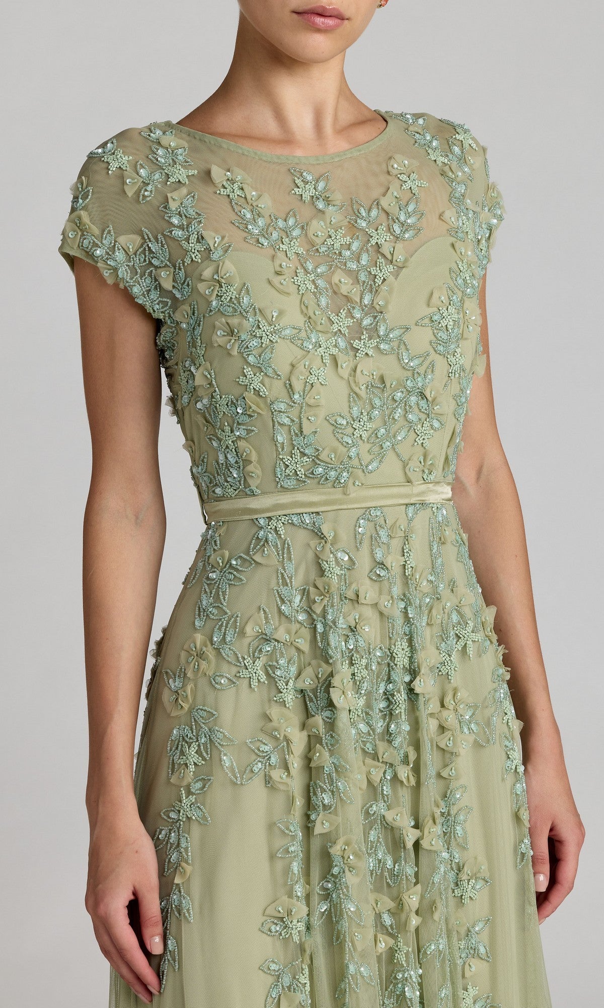 Woman wears the Mac Duggal 14521 Cap-Sleeve Long Formal Dress in light green, featuring intricate floral embroidery and a sheer neckline—ideal for special occasions.