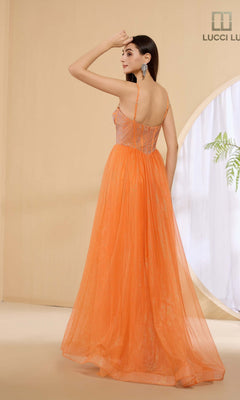 A woman stands indoors, facing away and touching her head, wearing the Lucci Lu 1457 long orange prom dress with a rhinestone corset bodice and thin straps; a round window with a plant is visible in the background.