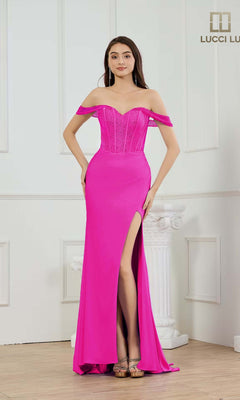 A woman models the Lucci Lu 1466 long prom dress in fuchsia, featuring an off-the-shoulder neckline, fitted corset bodice, and thigh-high slit, while standing indoors by a white decorative column.