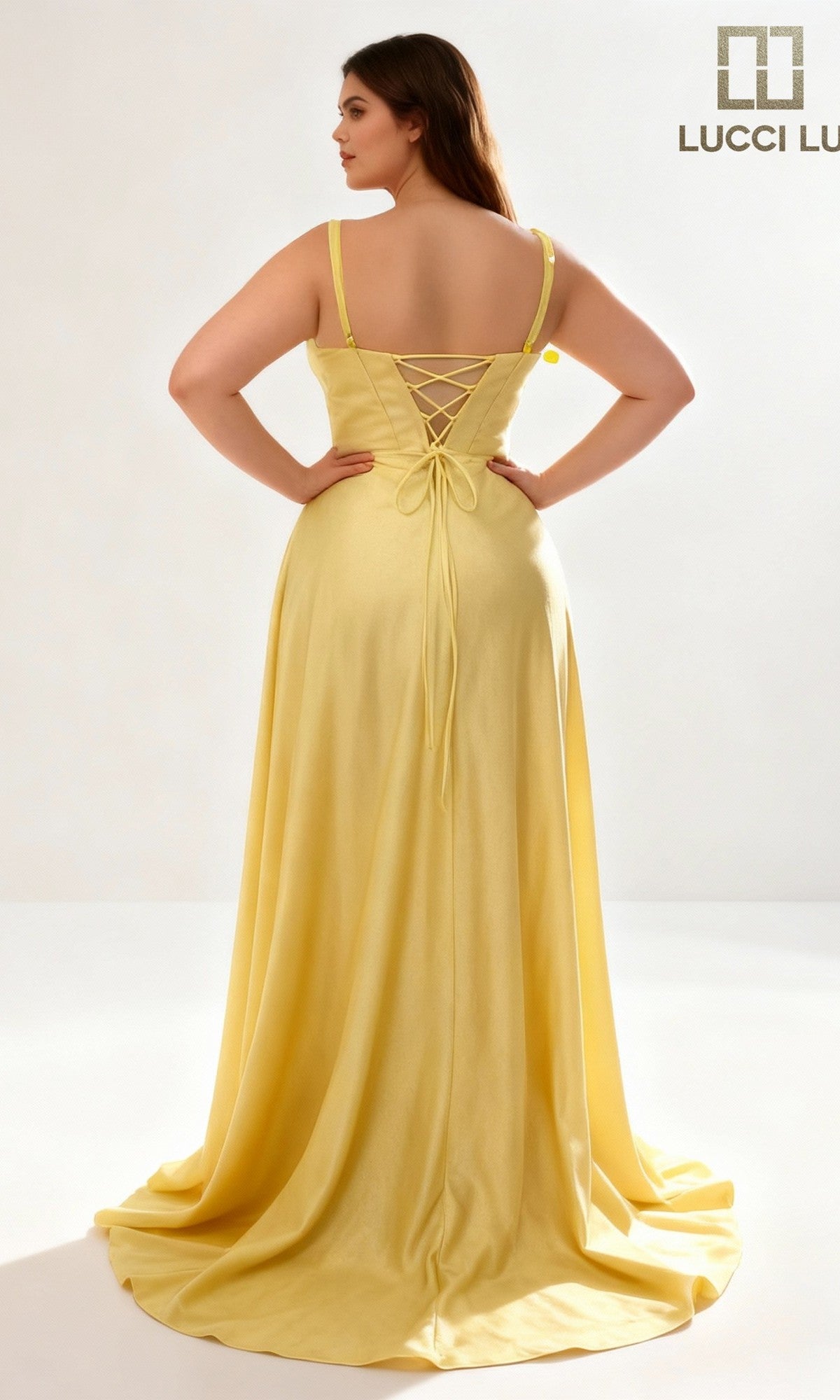 A woman wearing the Lucci Lu 1477 Long Prom Dress, a yellow sleeveless gown with an elegant A-line silhouette and lace-up back, stands facing away from the camera against a plain, well-lit background.