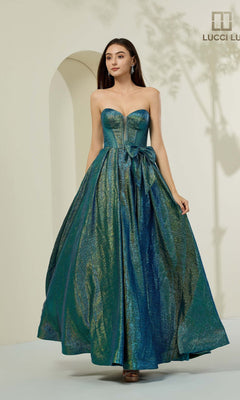 A woman stands in a well-lit room wearing the Lucci Lu 1481 long prom dress in teal, featuring a strapless shimmering corset bodice and a full skirt.