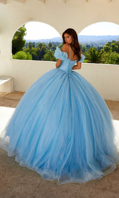 A young woman stands on a terrace in the Quinceanera Dress JT1487H By Juliet, a glitter tulle ball gown with puff off-the-shoulder sleeves, gazing over her shoulder at the trees and hills beyond.
