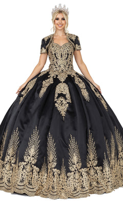 A woman in the Quinceanera Dress 1494 by Dancing Queen, a black a-line ball gown with gold lace embroidery and a matching crown, stands facing forward, holding out the sides of her dress.