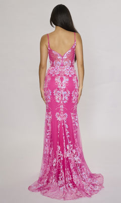 Woman in the Nina Canacci 1562 long formal dress, a fitted hot pink mermaid gown with white lace floral embroidery, poses with her back to the camera against a plain background.