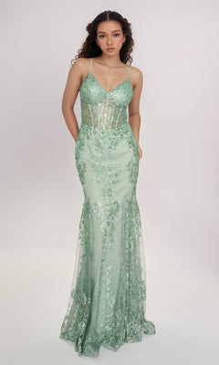 A woman wears the Nina Canacci 1562, a fitted light green long formal dress featuring spaghetti straps, a sheer corset-style bodice, hot stone embellishments, and a mermaid silhouette against a plain background.