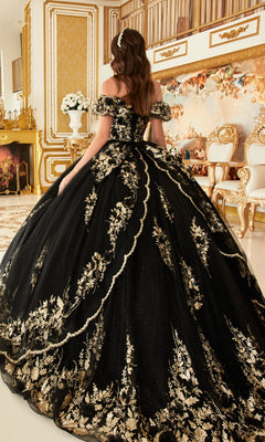 A woman in the Glitter Quince Dress with Back Bow: Ladivine 15701, featuring gold embroidery, stands in an opulent room adorned with gold accents and classical furnishings.