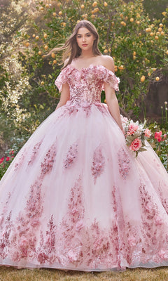 A young woman stands outdoors among greenery, holding a bouquet while wearing the Ladivine 15701 Glitter Quince Dress with Back Bow.