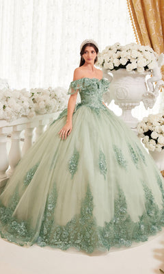 Wearing the Ladivine 15701 Glitter Quince Dress with a back bow, a woman stands indoors beside large white flowers, her pale green off-the-shoulder gown with floral embroidery evoking a dreamy fairytale vibe.