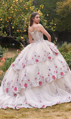 A young woman outdoors wears the Ladivine 15703 Glitter Champagne Quinceañera Dress, featuring floral embroidery and pink accents, as she looks over her shoulder.