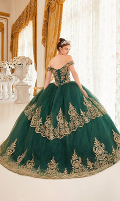 A young woman stands in an ornate room with large windows and gold curtains, wearing the Ladivine 15705 Quince Dress featuring elegant gold embroidery.