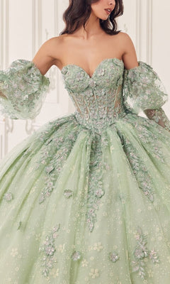 A woman wears the Quinceanera Dress 15722 by Ladivine—a strapless, pastel green ball gown with floral embroidery and removable puff sleeves—set against a light, ornate background.