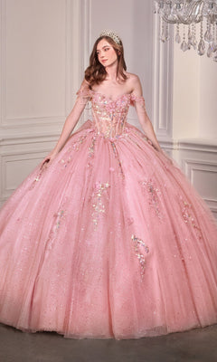 A woman in the Quinceanera Dress 15728 By Ladivine, a sparkling pink ball gown with off-the-shoulder sleeves and a tiara, stands in an elegant white-paneled room.