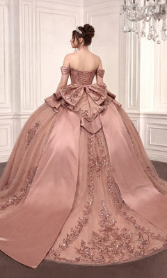 A woman stands facing away in an ornate room, wearing the Quinceanera Dress 15745 By Ladivine—a pink, off-the-shoulder ballgown featuring a beaded corset bodice and lace details.
