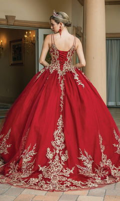 A woman in the Quinceanera Dress 1612 By Dancing Queen, a burgundy ball gown with gold lace embroidery, formal earrings, and a tiara stands outdoors near columns, facing away from the camera.