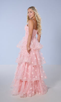 A woman with long blonde hair models the Long Prom Dress: Tiffany 16144, a pink floral gown with a ruffled A-line skirt, while standing sideways against a plain light blue background.