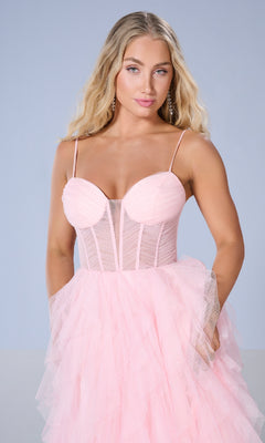 A woman with long blonde hair models the Tiffany 16161 Long Prom Dress, featuring a light pink corset bodice and layered tulle ball gown skirt, against a plain light blue background.