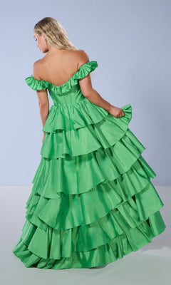 A woman faces away in the Tiffany 16175 long prom dress, featuring a bright green off-the-shoulder corset bodice and layered ruffled tiers, set against a plain light background.