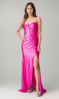 A woman wears the Nina Canacci 1617 long formal dress in fuchsia, featuring thin straps, a fitted corset bodice, sparkly details, a high slit, and floor-length design, paired with platform heels.