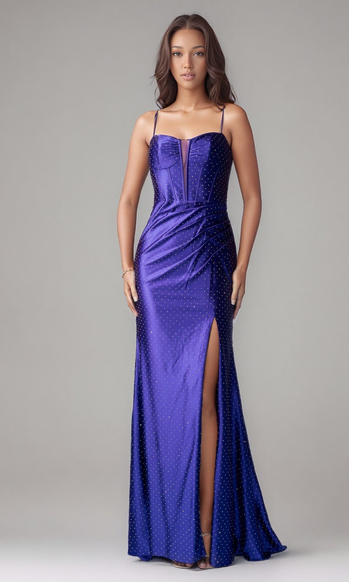 A woman poses against a plain light background in the Long Formal Dress: Nina Canacci 1617, a shiny purple gown with thin straps, a front slit, and subtle dotted embellishments perfect for special occasions.