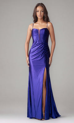 A woman poses against a plain light background in the Long Formal Dress: Nina Canacci 1617, a shiny purple gown with thin straps, a front slit, and subtle dotted embellishments perfect for special occasions.