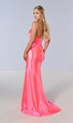 A woman with long blonde hair models the shiny, form-fitting Tiffany 16182 pink strapless long prom dress in a plain studio, looking over her shoulder.