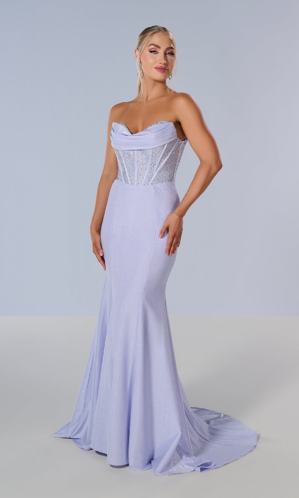 A woman models the Tiffany 16193 long prom dress—strapless, light lavender, floor-length—with a fitted, semi-sheer rhinestone corset bodice, set against a plain light background.