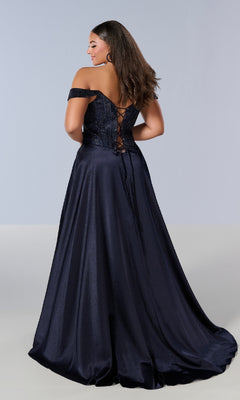 A woman models the Long Plus-Size Prom Dress: Tiffany 16204, featuring a dark off-the-shoulder design, lace-up corset back, flowing A-line skirt, and fitted bodice as she stands facing away.
