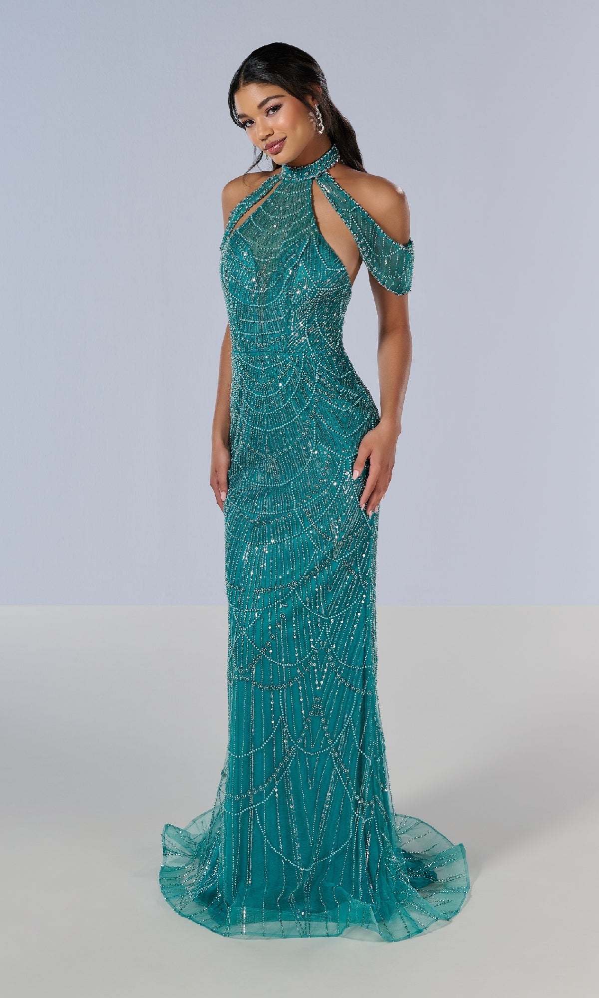 A woman models the Tiffany 16207 long prom dress, featuring a teal fitted floor-length design with intricate beading, cold shoulder cutouts, and a halter neckline, standing against a plain background.