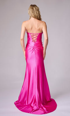 A woman models the Nina Canacci 1620, a strapless long formal dress in bright pink with a lace-up back, standing with her back to the camera against a plain backdrop.