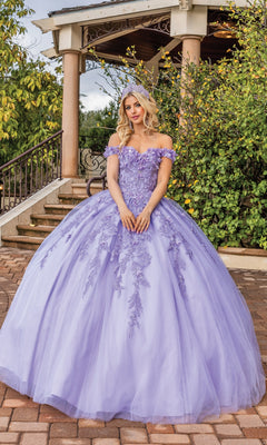 A woman wears the Quinceanera Dress 1620 By Dancing Queen, a voluminous lavender gown with floral embroidery, as she stands on a brick pathway before a gazebo surrounded by greenery.