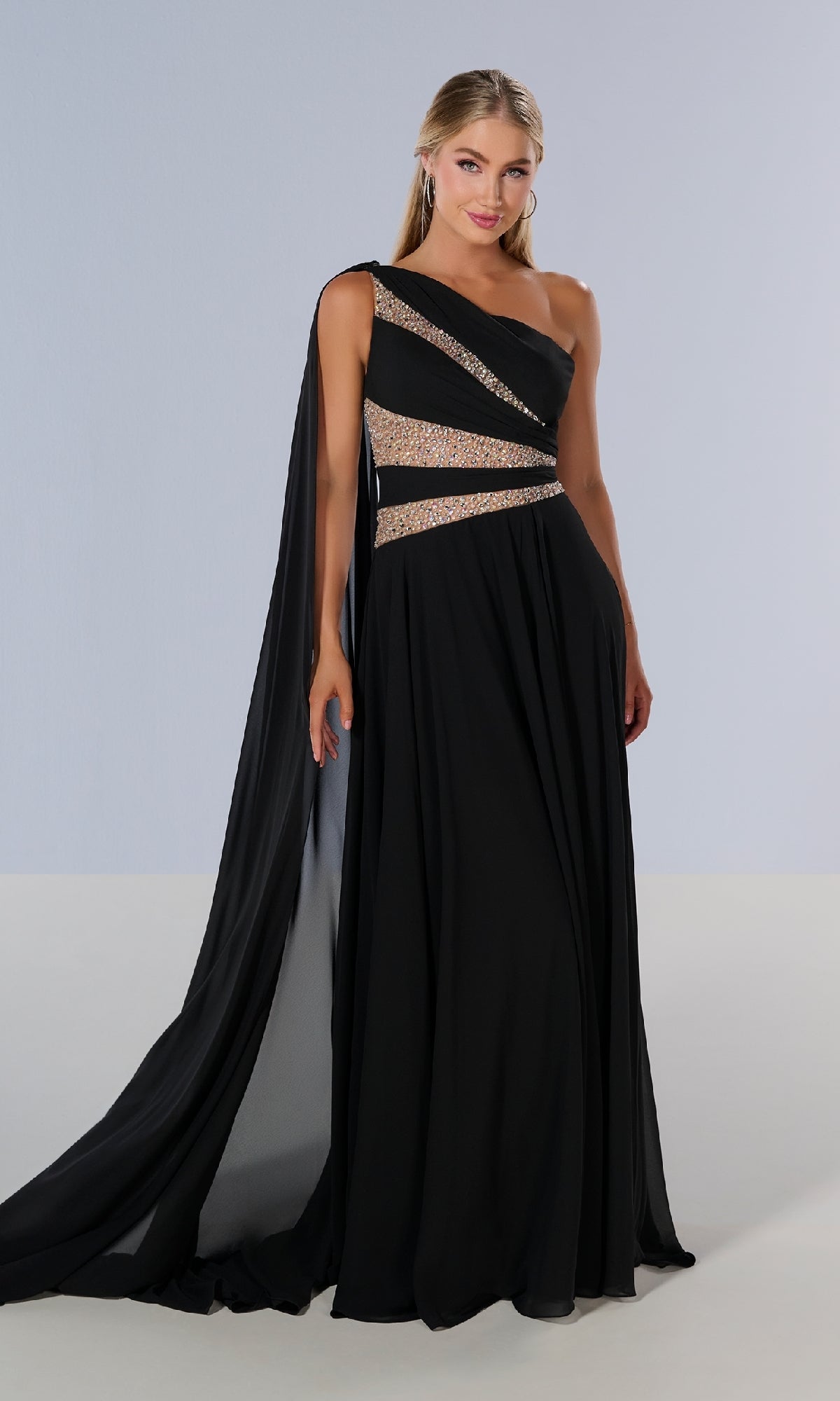 A woman models the Tiffany 16217 long prom dress—a black one-shoulder gown with gold and silver sequin accents and a flowing drape—standing against a plain light background.