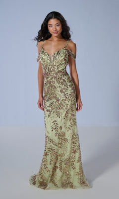 A woman wears the Tiffany 16230, a floor-length prom dress in pale green with gold and red intricate beadwork, spaghetti straps, and a slight sweetheart neckline.