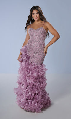A woman stands against a plain light background wearing the Tiffany 16234 long prom dress—a fitted, light purple mermaid gown featuring beaded details and layered ruffles on the lower half.
