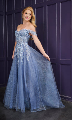 A woman models the Long Prom Dress: Tiffany 16243—an elegant blue off-the-shoulder gown with floral embroidery—as she poses gracefully against a purple paneled wall, holding out the skirt.