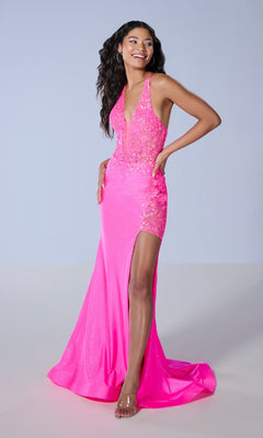 A woman stands against a plain light gray background wearing the Long Prom Dress: Tiffany 16246, featuring bright pink sequins, a corset bodice, and a thigh-high slit.