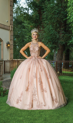A young woman wearing the Rose Gold Quinceanera Dress 1628 with a high neckline and crown smiles outdoors on grass, with trees and a building in the background.