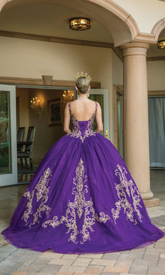 A woman in the Purple Quinceanera Dress 1635, featuring gold lace embroidery and a v-neckline, stands with her back to the camera in an elegant courtyard while wearing a gold crown.