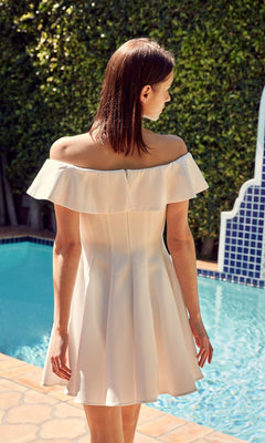 A woman wearing the Off-the-Shoulder Short Party Dress stands by a swimming pool, facing away from the camera with lush greenery in the background.