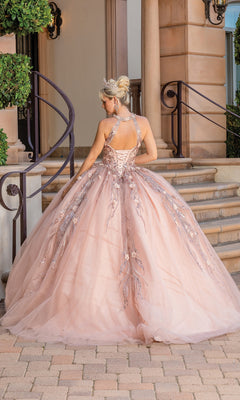 A woman in the Sleeveless Quinceanera Dress 1677, featuring pink floral embroidery and a corset back, stands on a stone path before a staircase, facing away from the camera.