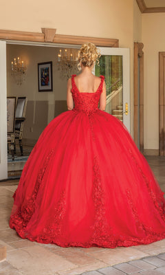 A woman with blonde hair in an updo wears the Quinceanera Dress 1678 By Dancing Queen, a red, floor-length ball gown with a full skirt and embroidered details, standing indoors and facing away from the camera.